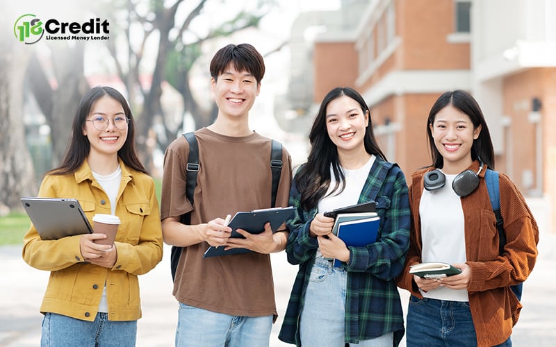 A group of four smiling students standing outdoors on a university campus