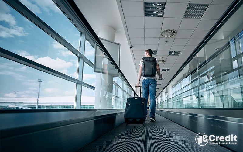 Person walking through an airport with luggage for travel.