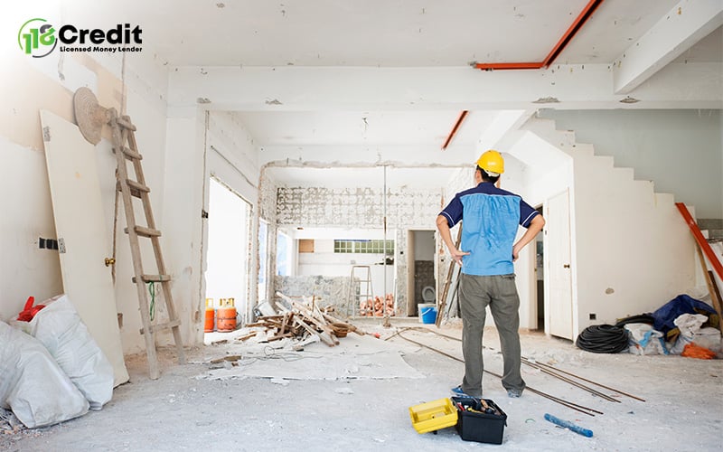 Construction worker standing inside a house undergoing major renovations.