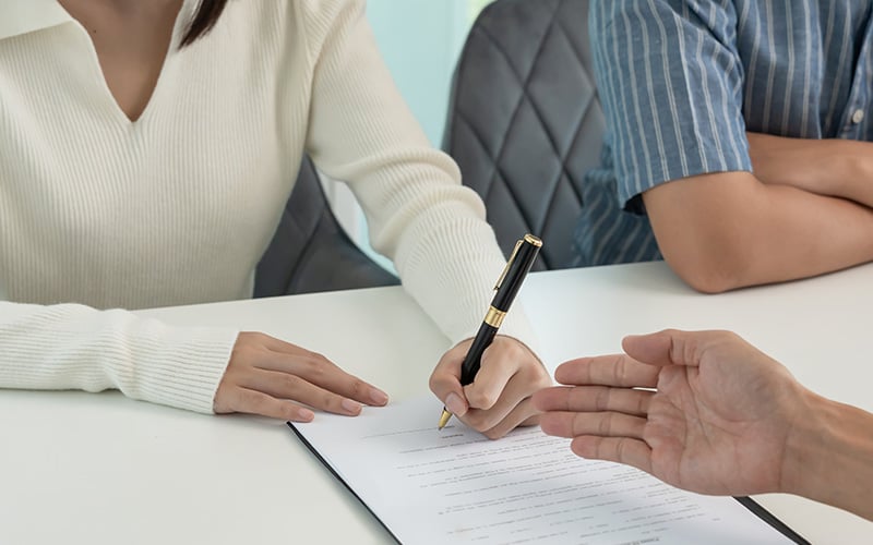 Close-up of a person signing a loan agreement.