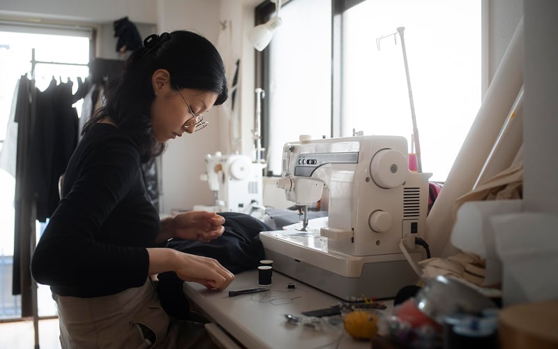 Woman tailoring clothes using funding to start a small business.