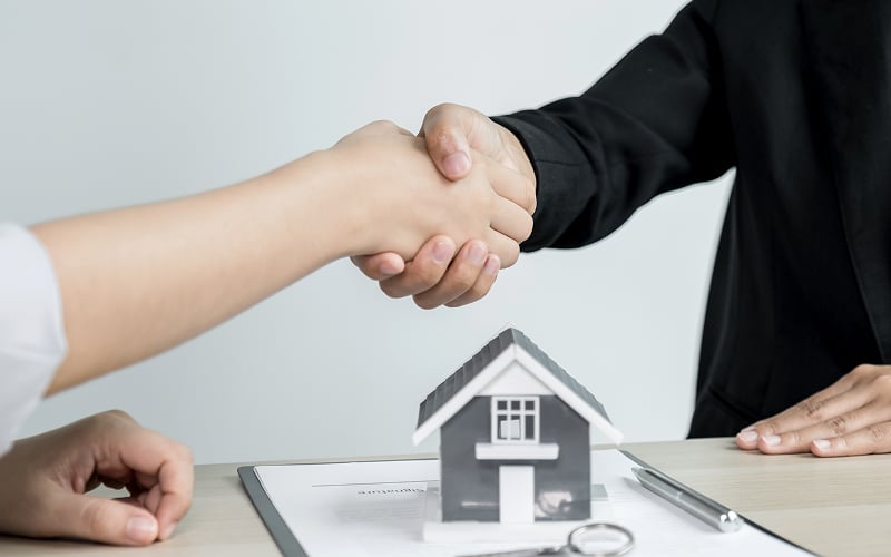 Client shaking hands over approved personal loan debt servicing ratio.