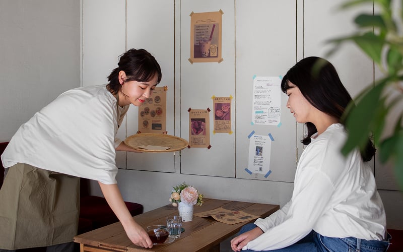 Part-time cafe worker serving drinks to customer in Singapore.